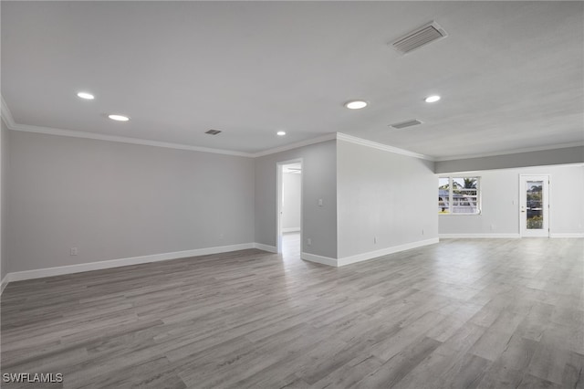 empty room with ornamental molding, wood finished floors, and visible vents