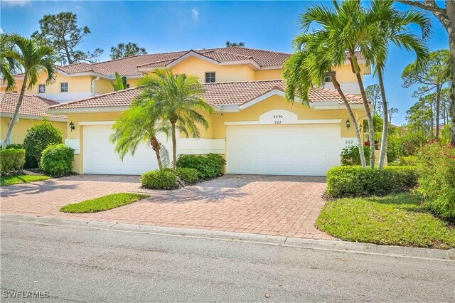 view of front of property with decorative driveway, an attached garage, and stucco siding