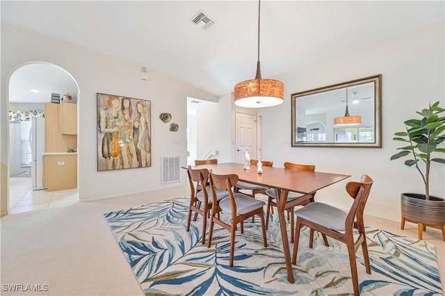 dining area with arched walkways, lofted ceiling, visible vents, and light colored carpet