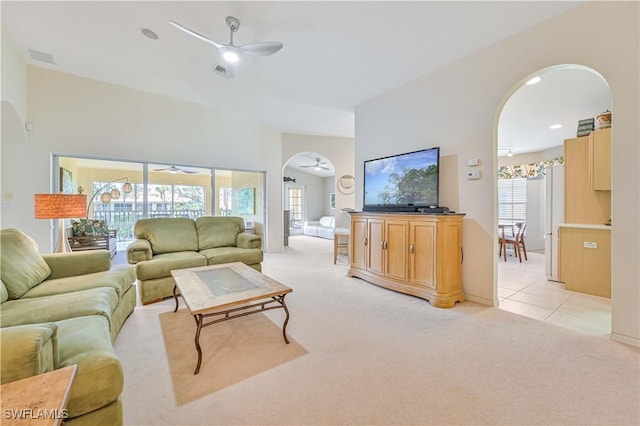 living room with light carpet, ceiling fan, and arched walkways