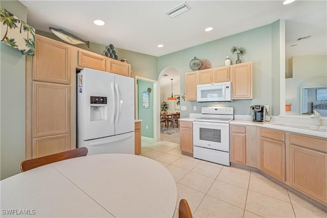 kitchen with light countertops, visible vents, light brown cabinetry, a sink, and white appliances