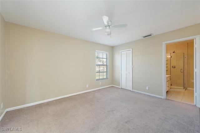 unfurnished bedroom featuring a closet, visible vents, ensuite bathroom, light carpet, and baseboards