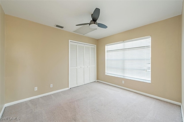 unfurnished bedroom featuring baseboards, visible vents, a ceiling fan, carpet floors, and a closet