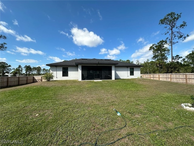 rear view of house featuring a yard, a fenced backyard, and stucco siding