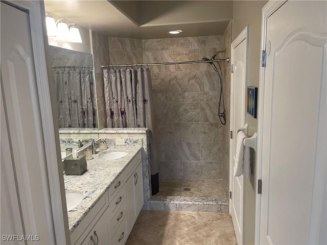 full bath featuring double vanity, tile patterned floors, a sink, and tiled shower