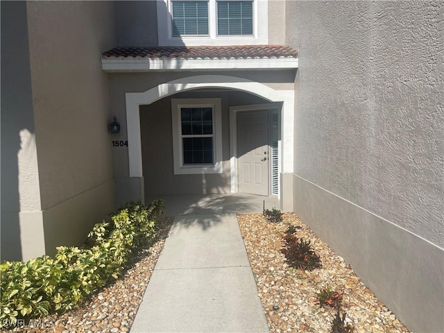 property entrance with a tiled roof and stucco siding