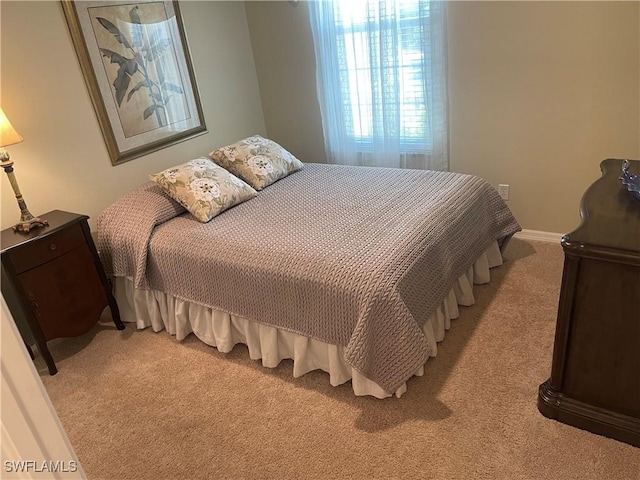 bedroom featuring light carpet and baseboards