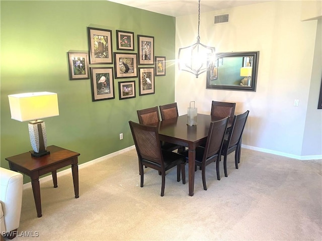 dining room featuring baseboards, a chandelier, visible vents, and light colored carpet