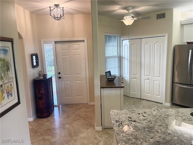 foyer with baseboards, visible vents, and ceiling fan