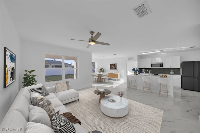 living area with marble finish floor, visible vents, ceiling fan, and baseboards