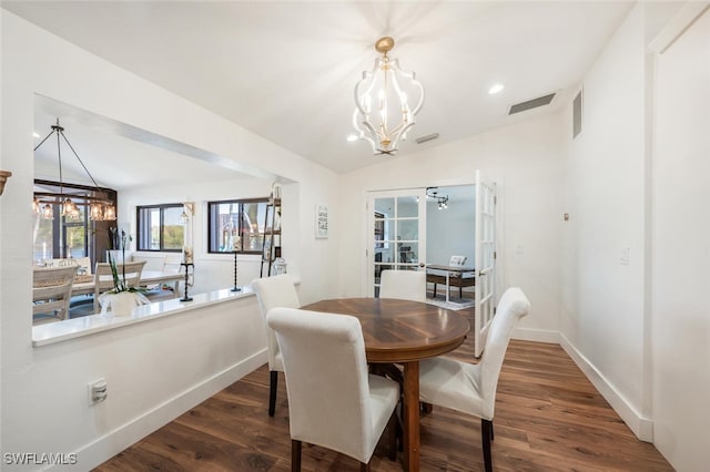 dining space featuring visible vents, a notable chandelier, baseboards, and wood finished floors