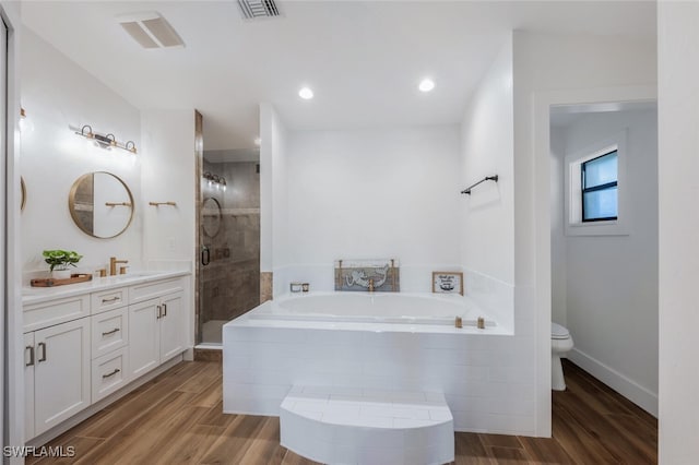 bathroom featuring wood tiled floor, a garden tub, vanity, and toilet