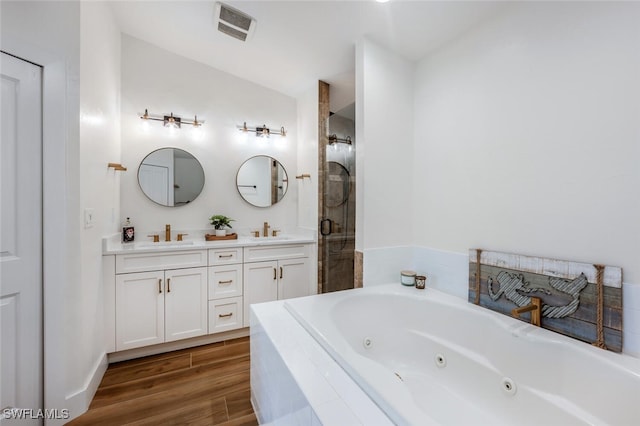 bathroom featuring double vanity, visible vents, a tub with jets, wood finished floors, and a shower stall