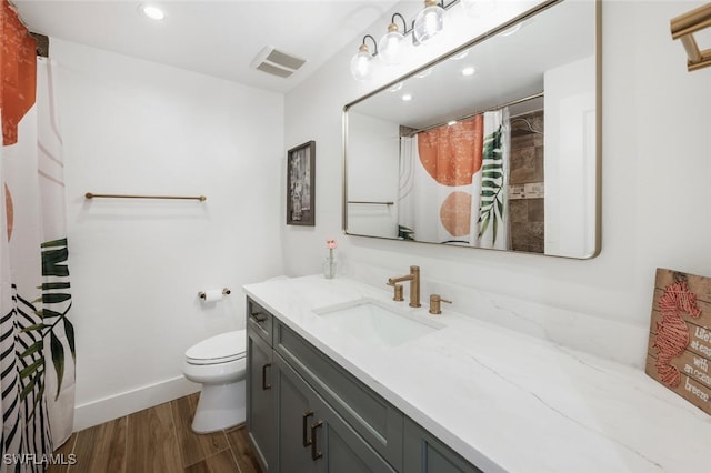 full bathroom featuring visible vents, toilet, vanity, wood finished floors, and baseboards