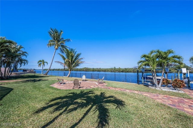 exterior space with a fire pit, a patio, a water view, and fence