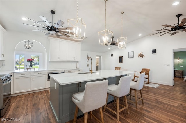 kitchen featuring electric range oven, an island with sink, a breakfast bar area, a sink, and ceiling fan with notable chandelier