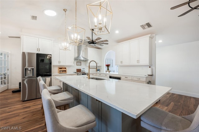 kitchen with wall chimney exhaust hood, a ceiling fan, stainless steel appliances, and a sink