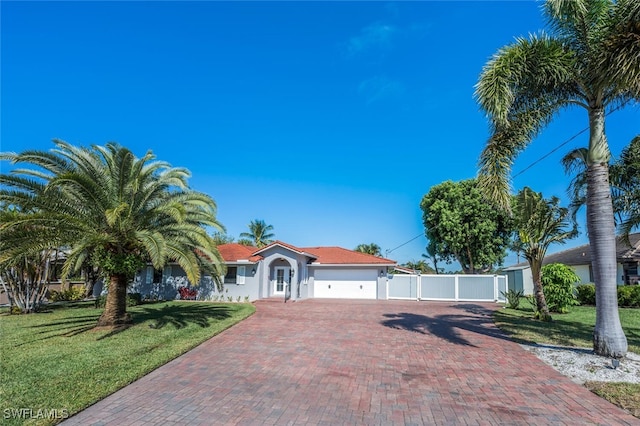 view of front facade featuring a garage, fence, decorative driveway, a front yard, and stucco siding