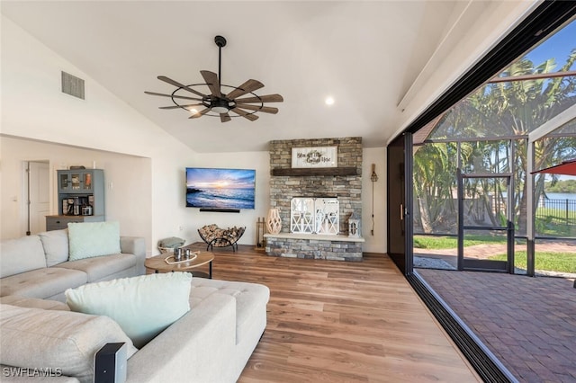 living area featuring high vaulted ceiling, a fireplace, wood finished floors, visible vents, and a ceiling fan