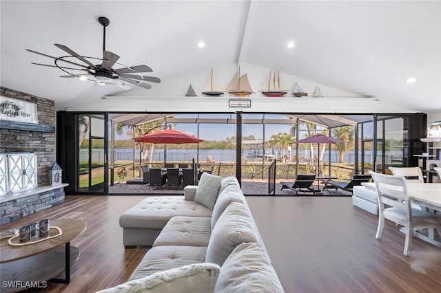 living room with a wealth of natural light, a ceiling fan, wood finished floors, and a stone fireplace