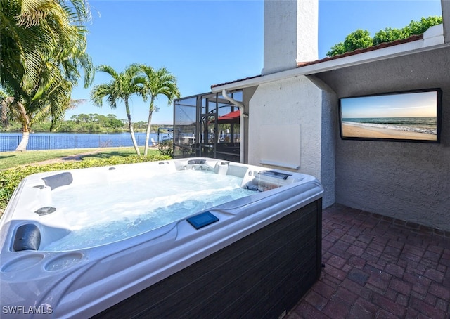 view of patio / terrace featuring glass enclosure, a water view, a hot tub, and fence