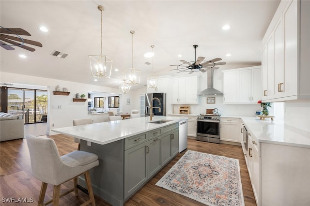 kitchen featuring a sink, a ceiling fan, open floor plan, wall chimney exhaust hood, and gas range