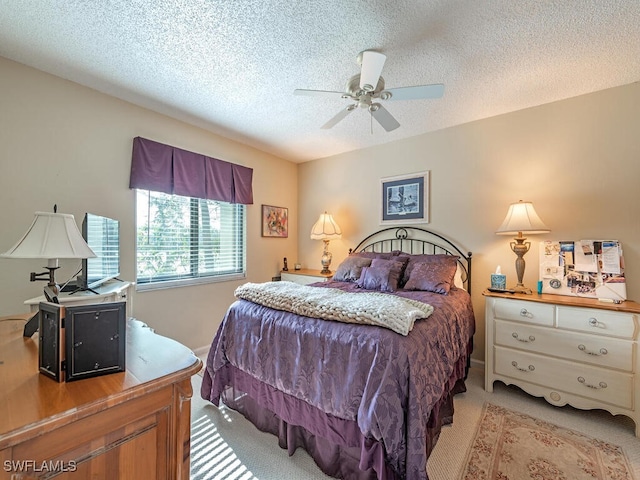 bedroom featuring a ceiling fan, light colored carpet, and a textured ceiling