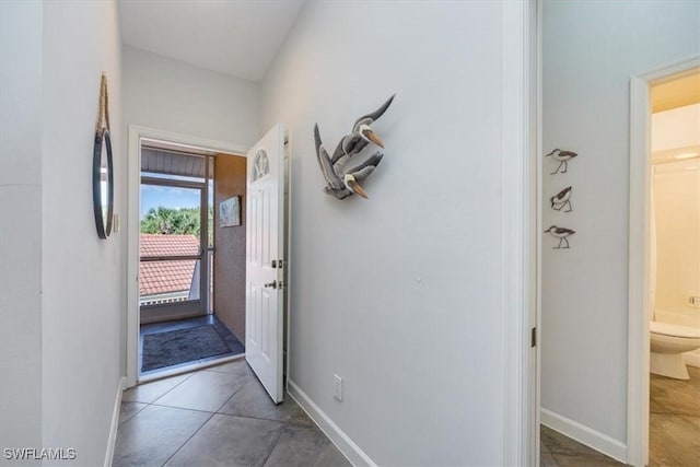 doorway featuring tile patterned flooring and baseboards