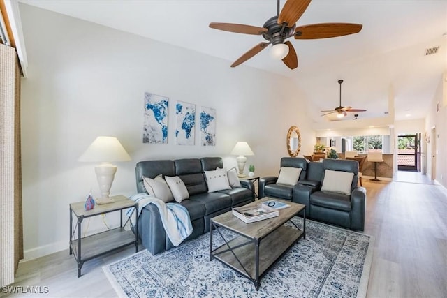 living area with light wood-type flooring, high vaulted ceiling, baseboards, and visible vents