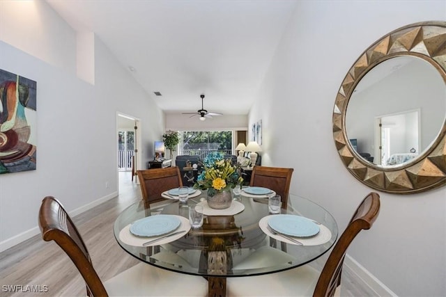 dining room featuring lofted ceiling, ceiling fan, wood finished floors, and baseboards