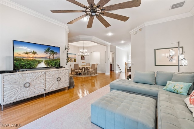 living area featuring visible vents, ornamental molding, ceiling fan with notable chandelier, wood finished floors, and baseboards