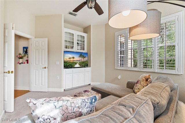 living area with a ceiling fan, carpet flooring, baseboards, and visible vents