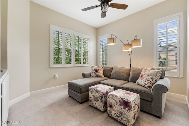 carpeted living room with baseboards and a ceiling fan