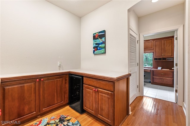 interior space featuring beverage cooler, light wood-style flooring, light countertops, and brown cabinets