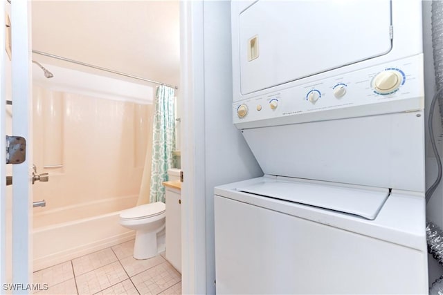 bathroom featuring toilet, shower / tub combo, tile patterned flooring, and stacked washer and clothes dryer