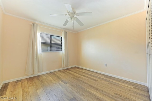 empty room featuring ornamental molding, light wood finished floors, and baseboards