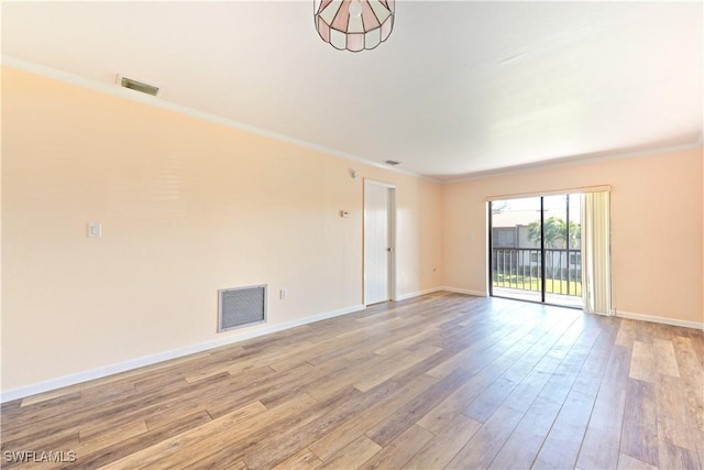 spare room with light wood-style floors, baseboards, visible vents, and ornamental molding