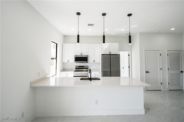 kitchen with stainless steel appliances, a sink, decorative light fixtures, and white cabinetry