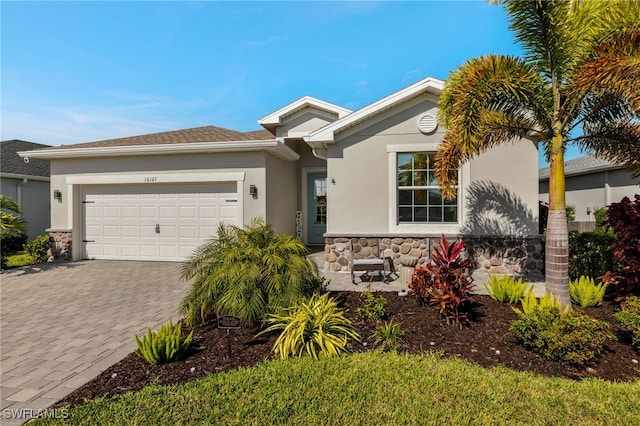 ranch-style home featuring stone siding, decorative driveway, an attached garage, and stucco siding