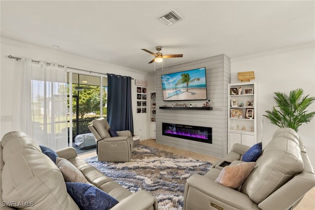 living room featuring ceiling fan, ornamental molding, a glass covered fireplace, and visible vents