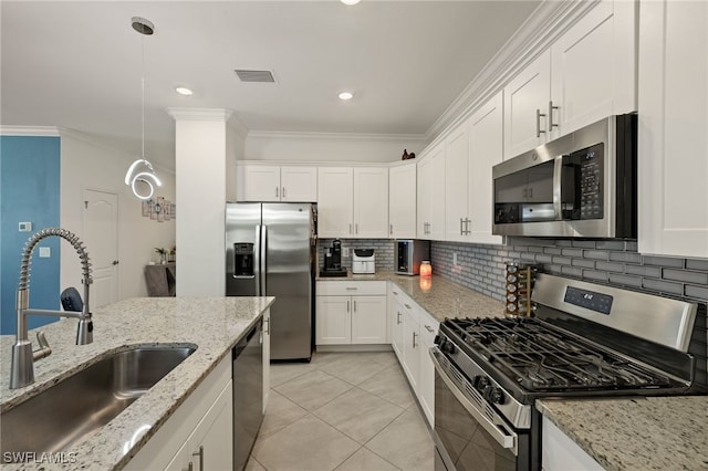 kitchen featuring stainless steel appliances, a sink, white cabinetry, hanging light fixtures, and light stone countertops