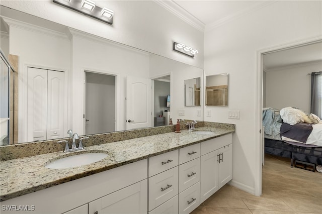 ensuite bathroom featuring tile patterned flooring, crown molding, a closet, and a sink