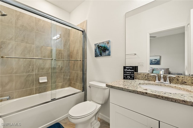 bathroom with enclosed tub / shower combo, vanity, and toilet