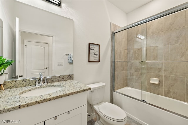 bathroom featuring toilet, bath / shower combo with glass door, and vanity