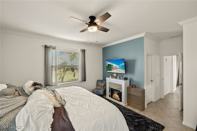 bedroom with light tile patterned floors, baseboards, a ceiling fan, a glass covered fireplace, and crown molding