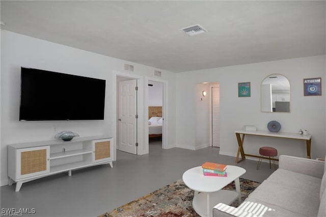 living area featuring finished concrete flooring, baseboards, and visible vents