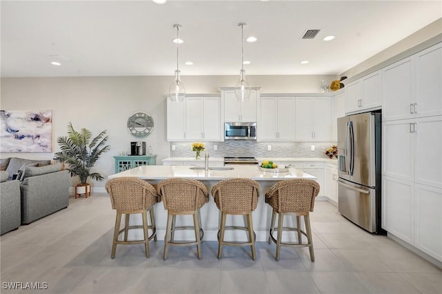 kitchen featuring stainless steel appliances, open floor plan, visible vents, and a breakfast bar area