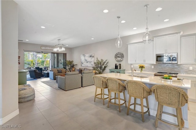 kitchen featuring appliances with stainless steel finishes, a breakfast bar, a sink, light countertops, and backsplash