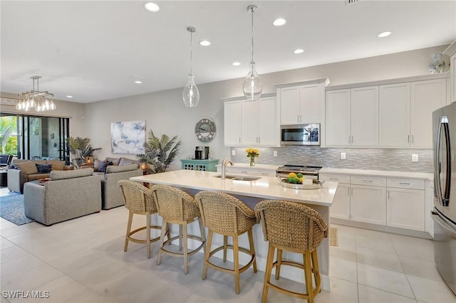 kitchen featuring light countertops, backsplash, appliances with stainless steel finishes, a sink, and a kitchen breakfast bar