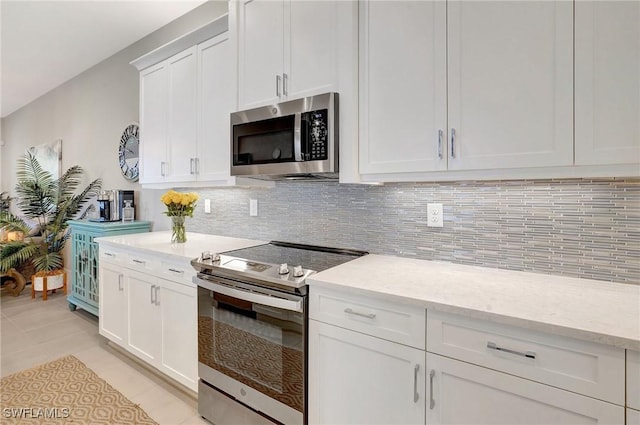 kitchen with white cabinets, light tile patterned floors, stainless steel appliances, and decorative backsplash